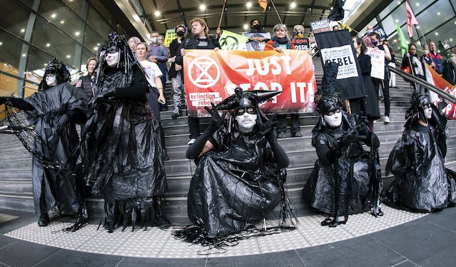 Oilies and XR rebels with Just Stop It banners on the steps of Southern Cross station, Melbourne. Photo Matt Hrkac.